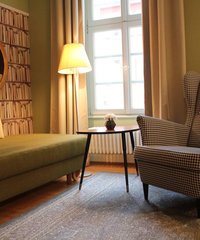Sitzbereich mit karierten Sessel und grünen Sofa 